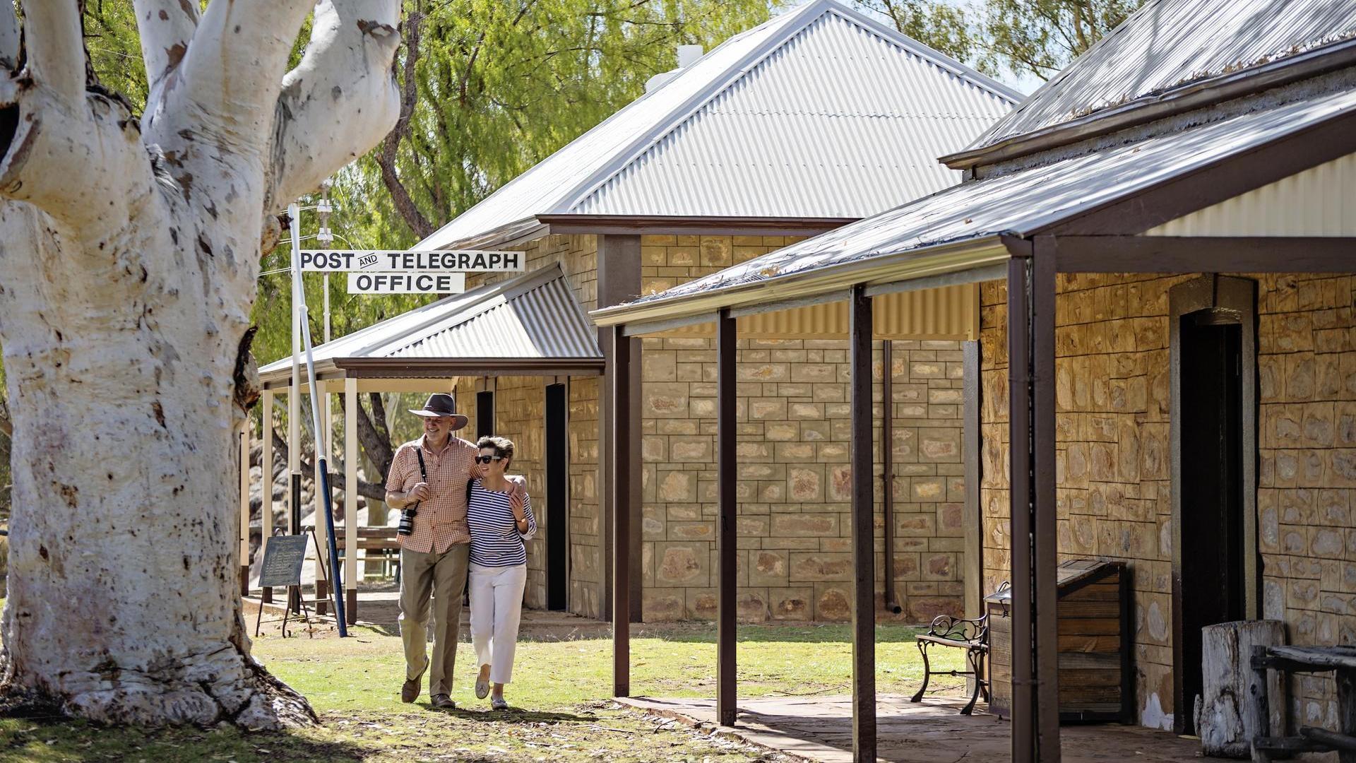A happy couple strolling by the historic buildings of the Alice Springs Telegraph Station