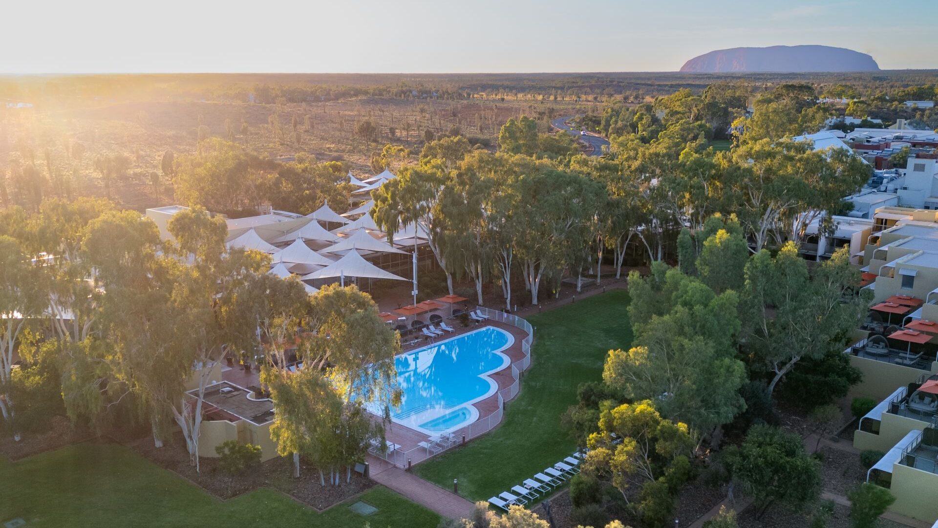 Ayers Rock Resort Aerial An aerial view of the pool at the resort at sunset with Uluru in the background